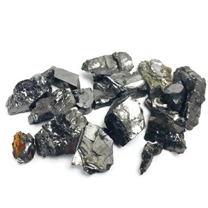 May include: A collection of black, irregularly shaped, and shiny pieces of raw, unpolished, natural, black,  mineral.