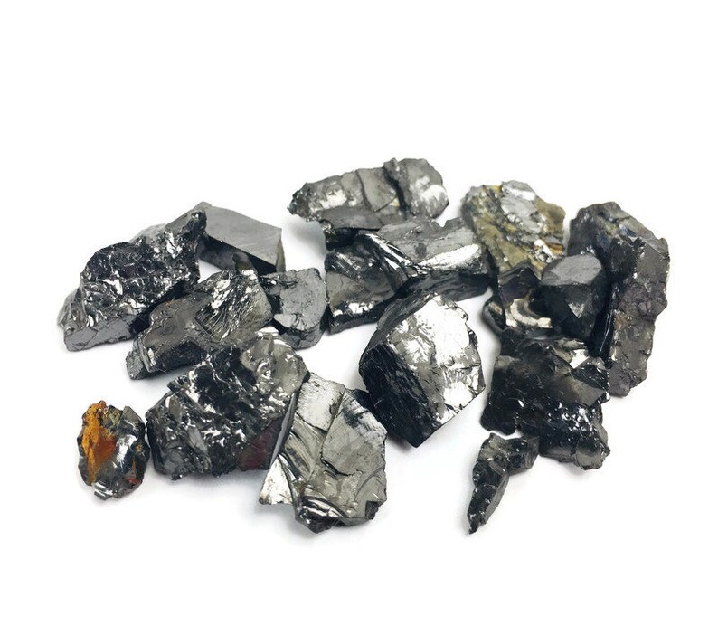 May include: A collection of black, irregularly shaped, and shiny pieces of raw, unpolished, natural, black,  mineral.