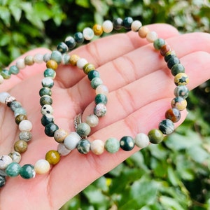 May include: A green, brown, and white gemstone bracelet with small round beads. The bracelet is made of natural stones and is a popular choice for those who enjoy wearing jewelry with a natural look.