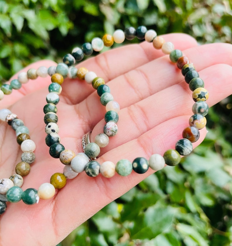 May include: A green, brown, and white gemstone bracelet with small round beads. The bracelet is made of natural stones and is a popular choice for those who enjoy wearing jewelry with a natural look.