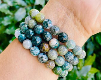 May include: A multi-layered bracelet made of green, blue, and brown agate beads. The beads are round and have a mottled, speckled appearance.