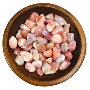 May include: A bowl filled with pink and white agate tumbled stones. The stones are smooth and polished, with a variety of patterns and colors.