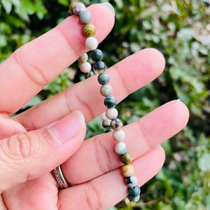 May include: A bracelet made of green, white, and brown gemstone beads. The beads are round and have a natural, polished finish.