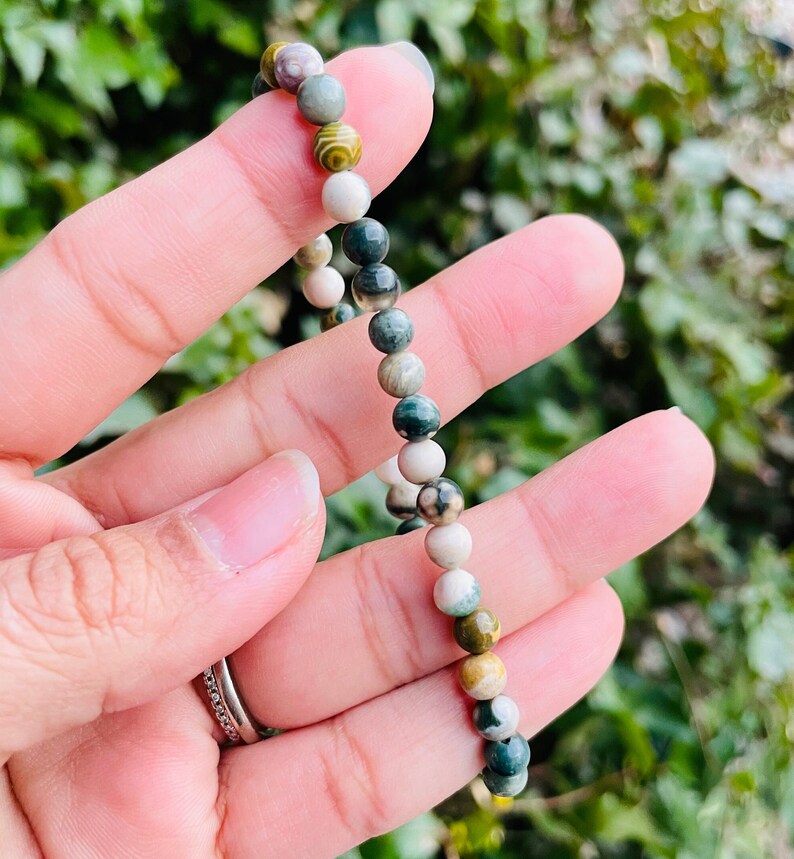 May include: A bracelet made of green, white, and brown gemstone beads. The beads are round and have a natural, polished finish.