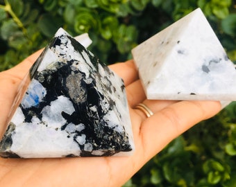 Puede incluir: Dos pirámides de piedra lunar blanca y negra. La pirámide de la izquierda tiene un patrón negro más pronunciado. La pirámide de la derecha es principalmente blanca con algunas manchas negras.