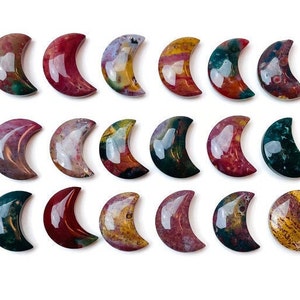 May include: A collection of 18 polished, crescent-shaped, agate stones in various shades of red, brown, green, and yellow. The stones are arranged in three rows of six.
