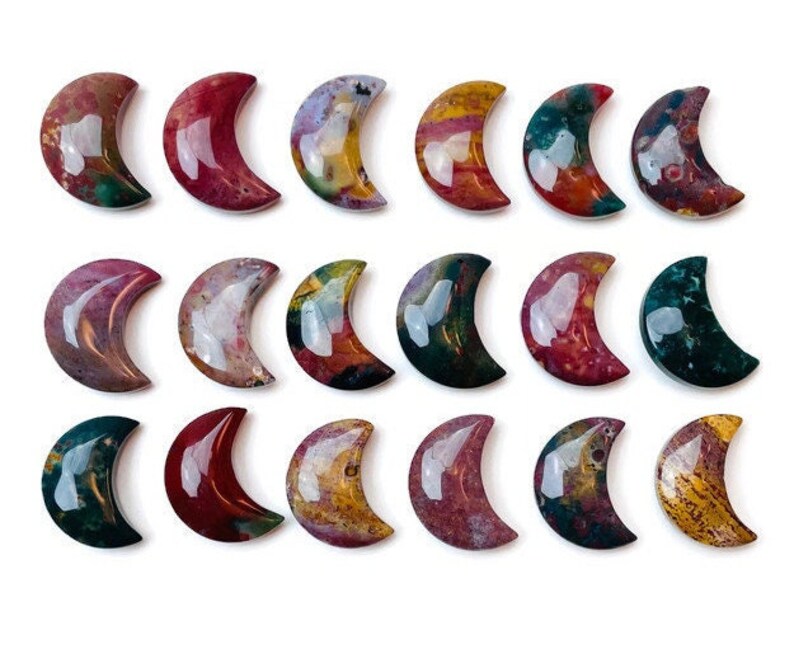May include: A collection of 18 polished, crescent-shaped, agate stones in various shades of red, brown, green, and yellow. The stones are arranged in three rows of six.