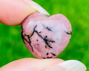 May include: Pink heart-shaped stone with black veins. The stone is smooth and polished.