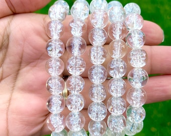 May include: Five clear crystal bracelets with a sparkly, iridescent finish. Each bracelet is made of round beads and is stacked on top of each other.