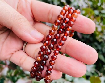 May include: A bracelet made of multiple strands of small, round, red-brown garnet beads.