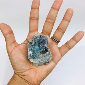 Op de afbeelding: Een blauw en groen fluorietkristal met een ruwe, natuurlijke textuur. Het kristal is ongeveer 5 cm breed en 4 cm hoog.