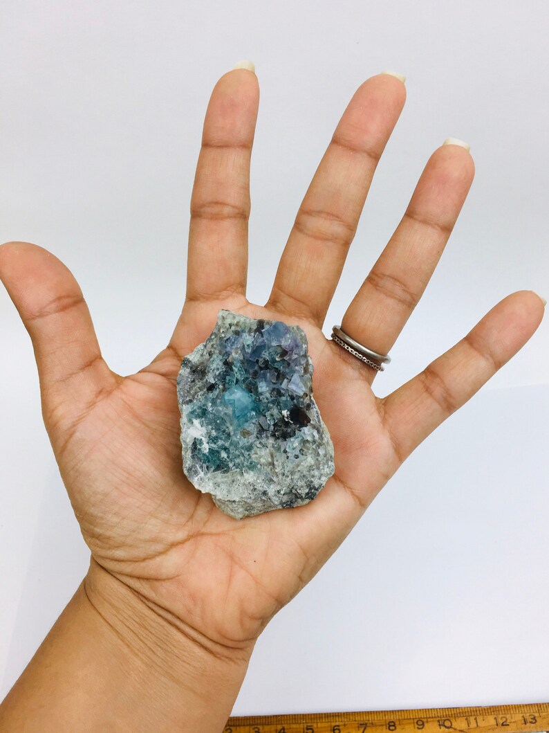 Op de afbeelding: Een blauw en groen fluorietkristal met een ruwe, natuurlijke textuur. Het kristal is ongeveer 5 cm breed en 4 cm hoog.