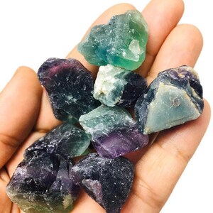 Pu&ograve; includere: Una collezione di cristalli di fluorite di colore verde, viola e blu. I cristalli sono grezzi e hanno un aspetto naturale non levigato.