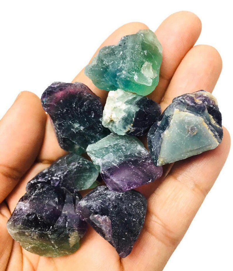 Pu&ograve; includere: Una collezione di cristalli di fluorite di colore verde, viola e blu. I cristalli sono grezzi e hanno un aspetto naturale non levigato.