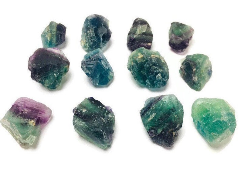 Pu&ograve; includere: Una collezione di 12 cristalli di fluorite di colore verde, blu e viola. I cristalli sono grezzi e hanno una variet&agrave; di forme e dimensioni.