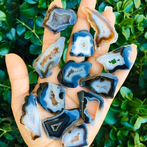May include: A collection of 12 agate slices with black and white banding and a natural crystal cave. The agate slices are various shapes and sizes.
