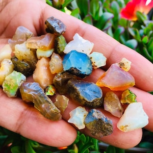 May include: A collection of rough, colorful opal gemstones in various shapes and sizes. The opals are a mix of blue, green, orange, pink, and white.