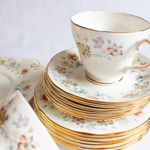 May include: A vintage tea set with floral pattern and gold trim. The cups and saucers are stacked on top of each other.