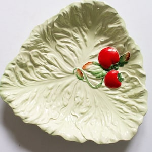 May include: A white ceramic serving dish shaped like a lettuce leaf with two red tomatoes on a vine.