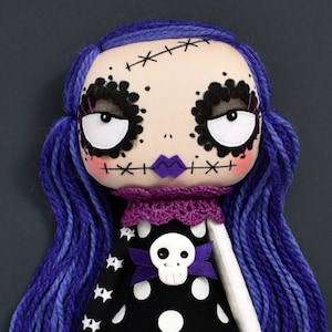 close-up of dark cute gothic fabric doll face with large round eyes, multi-toned purple hair, black dress with stars and polka dots from sewing tutorial with printable PDF pattern