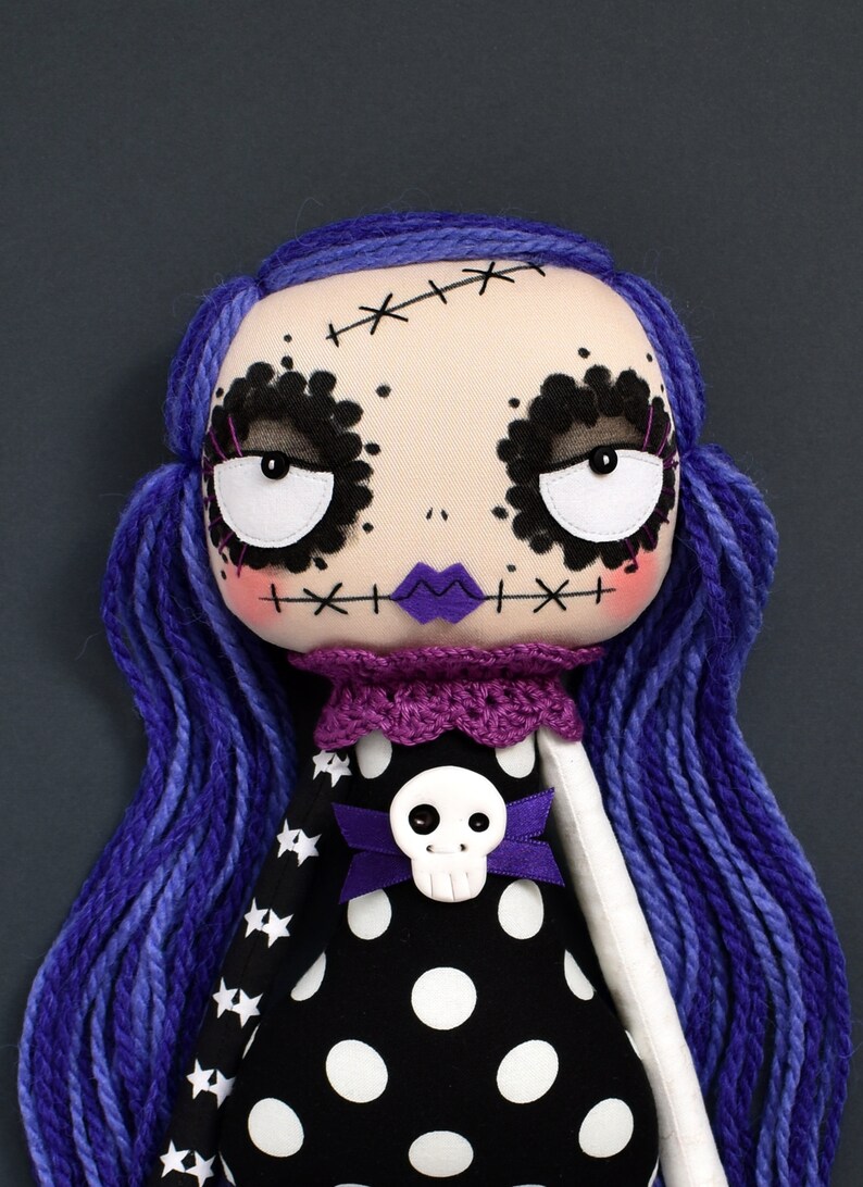 close-up of dark cute gothic fabric doll face with large round eyes, multi-toned purple hair, black dress with stars and polka dots from sewing tutorial with printable PDF pattern