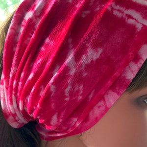 May include: A pink and white tie-dye headband made of soft fabric. The headband is folded and worn on a person's head.