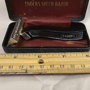 May include: A black and silver Enders Speed Razor in its original black case with a red interior. The razor has a black plastic handle and a silver blade. The case has the words "Enders Speed Razor" printed on the inside.