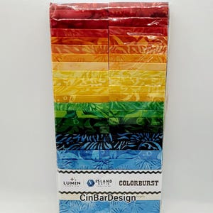 May include: A pack of 40 2.5-inch fabric squares in a rainbow color gradient. The fabric is batik and features a floral pattern. The pack is labeled "Island Batik" and "Colorburst" with the text "CinBarDesign" at the bottom.