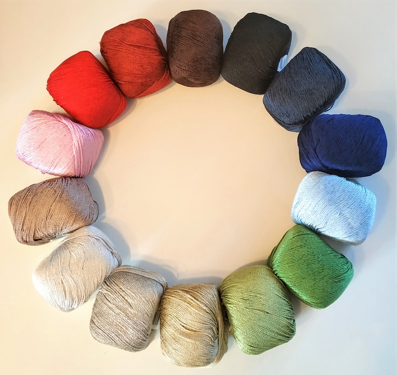 Może przedstawiać: Koło z kłębk&oacute;w wł&oacute;czki w r&oacute;żnych kolorach, w tym r&oacute;żowym, niebieskim, zielonym, brązowym i czerwonym. Kłębki wł&oacute;czki są ułożone w k&oacute;łko na białym tle.