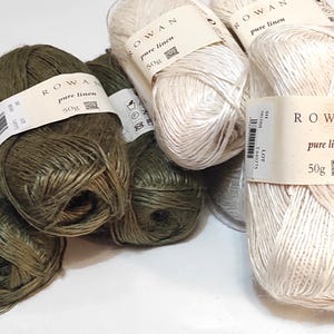 Peut inclure: Quatre pelotes de fil Rowan Pure Linen, deux de couleur blanc naturel et deux de couleur vert foncé. Chaque pelote est étiquetée avec le logo Rowan et les mots "Pure Linen" et "50g".