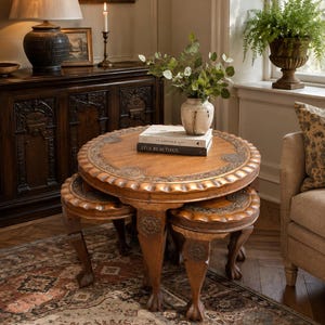 May include: A round wooden nesting table set featuring carved scalloped edges and intricate circular motifs on the tabletop and legs. The tables have cabriole legs with claw-and-ball feet, finished in a warm brown tone with visible wood grain.