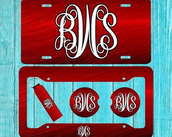 Puede incluir: Un marco de matrícula de metal rojo con un monograma blanco "BWC" en el centro. El marco forma parte de un conjunto que incluye dos posavasos a juego y un llavero, todos con el mismo monograma.