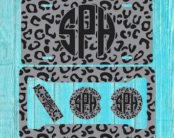 May include: A set of three personalized items featuring a black and gray leopard print design. The set includes a license plate, a keychain, and two coasters. Each item features a black circle with the monogram "SPH" in white.