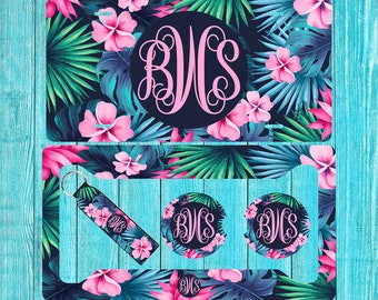 May include: A set of four tropical-themed car accessories featuring a pink monogram "BWS" on a dark blue background with green palm leaves and pink hibiscus flowers. The set includes a license plate frame, a keychain, and two round coasters.