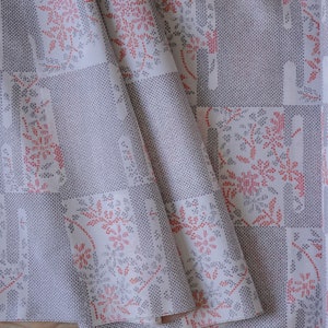 Pode incluir: Tecido branco com um padrão xadrez e um design floral vermelho e azul. O tecido está dobrado ao meio e as bordas são visíveis.