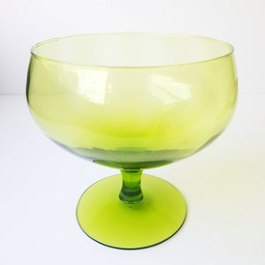May include: A green glass goblet with a wide bowl and a short stem. The goblet is clear at the top and gradually becomes a darker green towards the bottom.