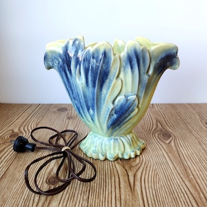 May include: A vintage ceramic lamp base with a yellow and blue floral design. The lamp base has a cord and plug.