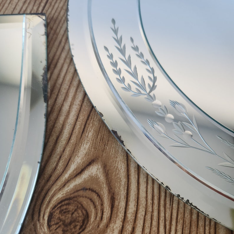 Puede incluir: Dos espejos antiguos de vidrio biselado con dise&ntilde;os florales grabados. El espejo m&aacute;s grande es redondo y tiene un dise&ntilde;o floral alrededor del borde. El espejo m&aacute;s peque&ntilde;o es rectangular y tiene un dise&ntilde;o m&aacute;s simple.