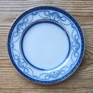 May include: A white porcelain saucer with a blue and gold floral pattern. The saucer has a scalloped edge and is perfect for serving tea or coffee.