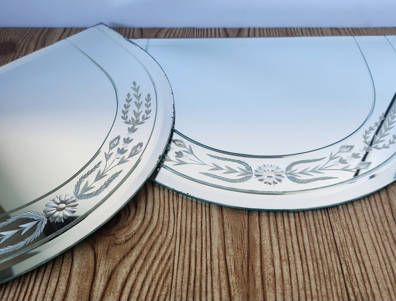 Puede incluir: Dos espejos decorativos de vidrio grabado con un dise&ntilde;o floral. Los espejos son de media luna y tienen un borde biselado.