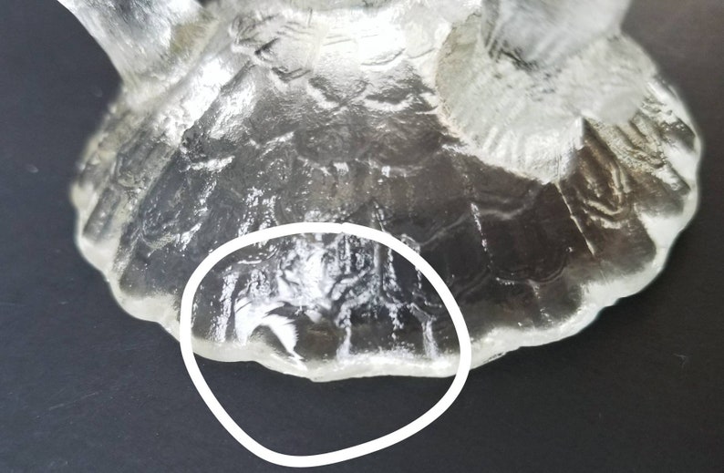 Może przedstawiać: Zbliżenie na sp&oacute;d przezroczystego dzbanka ze szkła z fakturowanym wzorem. Szkło ma falisty brzeg.