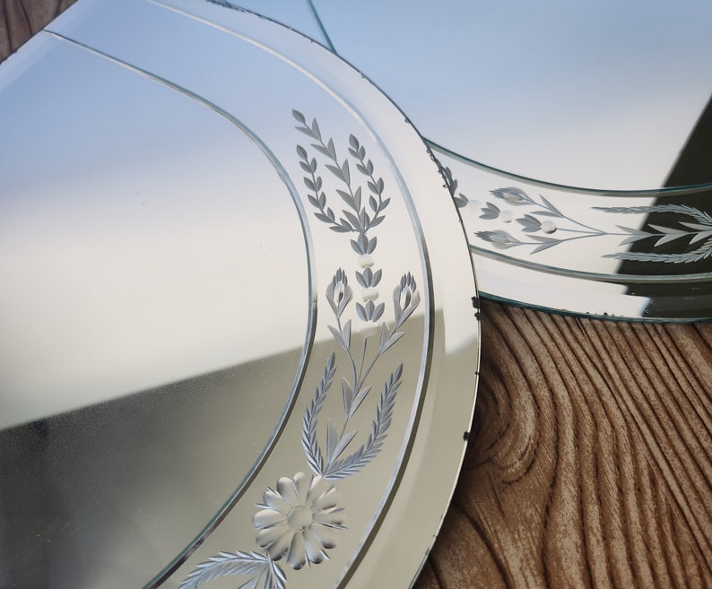 Puede incluir: Dos espejos ovalados con dise&ntilde;os florales grabados. Los espejos son plateados y tienen un borde biselado.