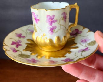 Taza de té pequeña de porcelana victoriana antigua, ornamentada y pintada a mano con violetas.
