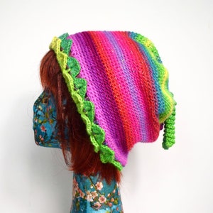 May include: A vibrant knitted hat featuring a striped pattern in pink, purple, blue, and green. The hat is trimmed with a green scalloped edge and a matching green tassel. The hat is displayed on a mannequin head.
