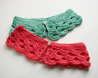 May include: Two crocheted headbands, one in a vibrant red and the other in a soft green. Each headband features a scalloped edge and a decorative pearl button closure. The handmade headbands are displayed on a white surface.