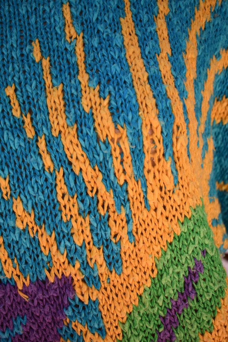 May include: Close-up of a knitted fabric with a striped pattern in shades of blue, yellow, green, and purple.