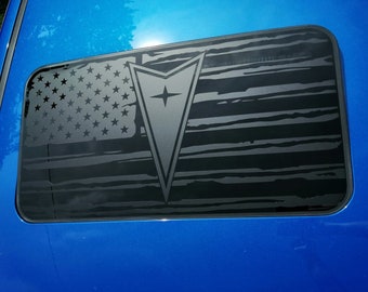 May include: A blue car with a black and white American flag decal on the sunroof. The flag is distressed and has a stylized arrowhead in the center.