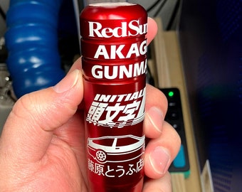 May include: Red Sun Akagi Gunma Initial D shift knob with a red finish and white lettering. The knob features a car graphic and the text "Red Sun Akagi Gunma Initial D" and "源とらふ店".