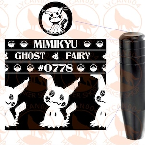 May include: A black cylindrical gear shift knob featuring a graphic print of the character Mimikyu. The design includes the text Mimikyu, Ghost, Fairy, and #0778, along with small circular icons resembling Poké Balls on a black background.