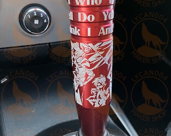 May include: A red shift knob with white text that reads "Who The Hell Do You Think I Am". The knob has a detailed white graphic design and is installed in a car.
